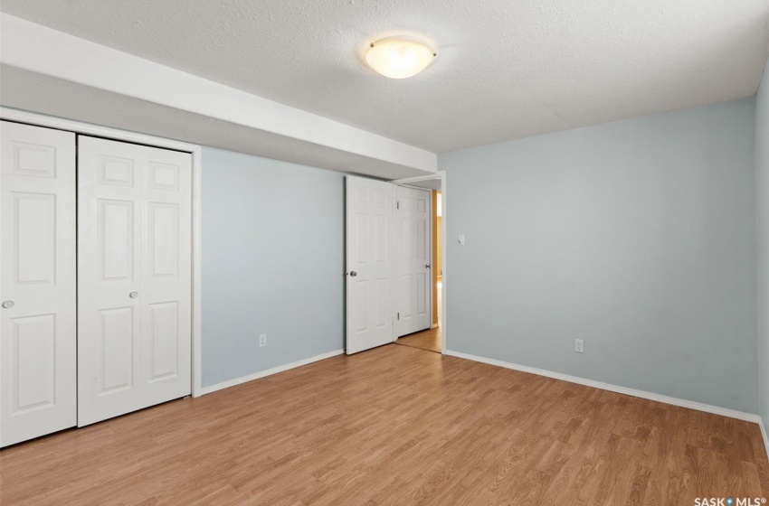 Unfurnished bedroom featuring a textured ceiling, a closet, and light hardwood / wood-style flooring