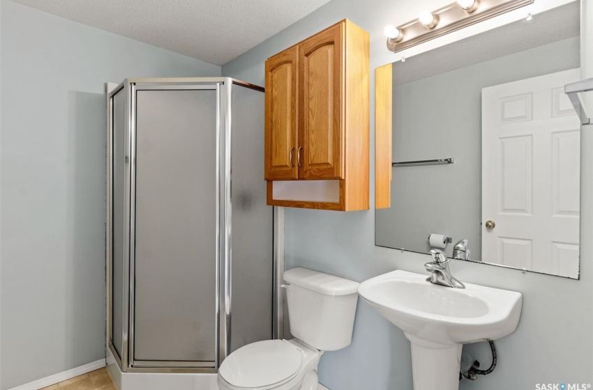 Bathroom featuring tile floors, toilet, a shower with shower door, and a textured ceiling