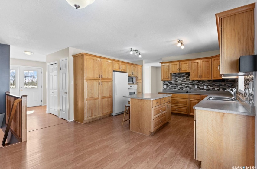 Kitchen featuring a kitchen island, white appliances, sink, light hardwood / wood-style flooring, and rail lighting