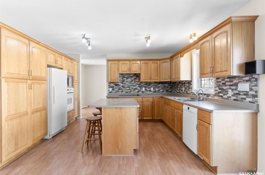 Kitchen featuring a kitchen island, a breakfast bar, white appliances, sink, and light hardwood / wood-style flooring