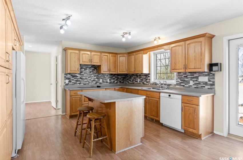 Kitchen featuring white appliances, a kitchen island, rail lighting, and light hardwood / wood-style flooring