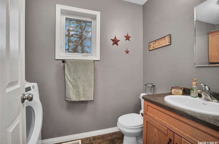 Bathroom with washer / clothes dryer, toilet, tile flooring, and oversized vanity