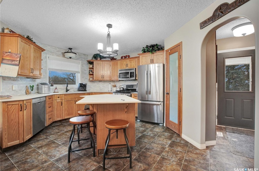 Kitchen with a kitchen island, tasteful backsplash, a chandelier, hanging light fixtures, and appliances with stainless steel finishes