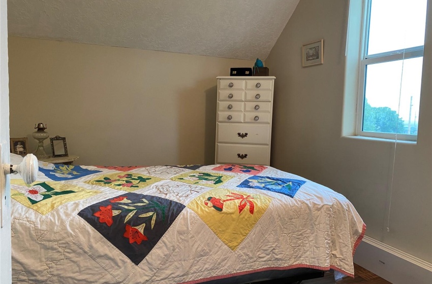 Bedroom featuring dark hardwood / wood-style floors, vaulted ceiling, and a textured ceiling