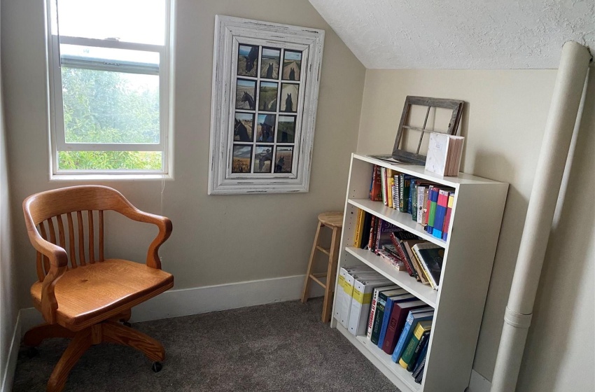 Reading area with vaulted ceiling, dark colored carpet, and a textured ceiling