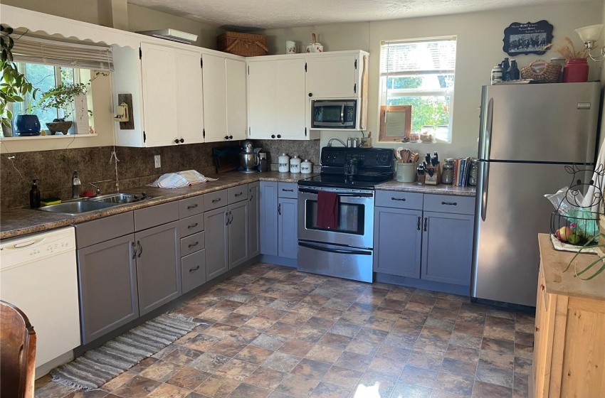 Kitchen featuring tasteful backsplash, gray cabinets, appliances with stainless steel finishes, and dark flooring