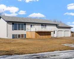 View of front of property with a wooden deck, a front lawn, and a garage