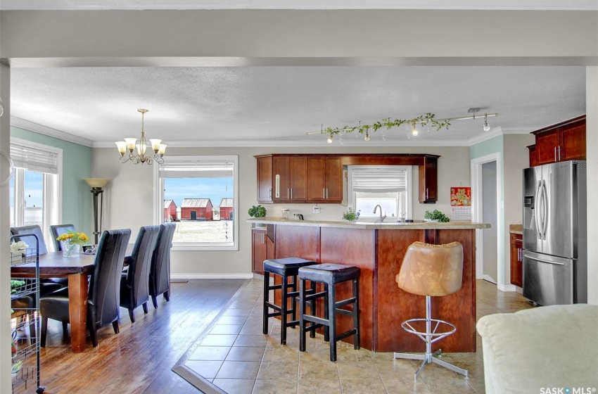 Kitchen with crown molding, wood-type flooring, pendant lighting, stainless steel refrigerator with ice dispenser, and an inviting chandelier