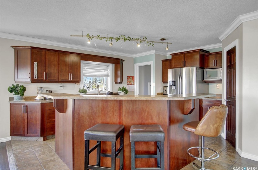 Kitchen with appliances with stainless steel finishes, crown molding, a textured ceiling, rail lighting, and a breakfast bar