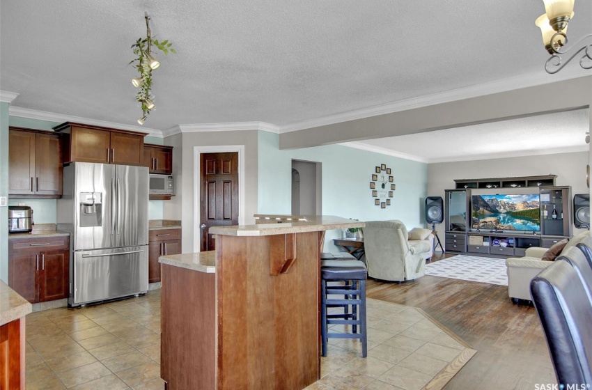 Kitchen with a kitchen island, white microwave, stainless steel fridge, ornamental molding, and a kitchen breakfast bar