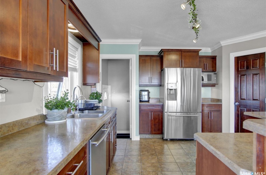 Kitchen featuring stainless steel appliances, a textured ceiling, rail lighting, sink, and ornamental molding