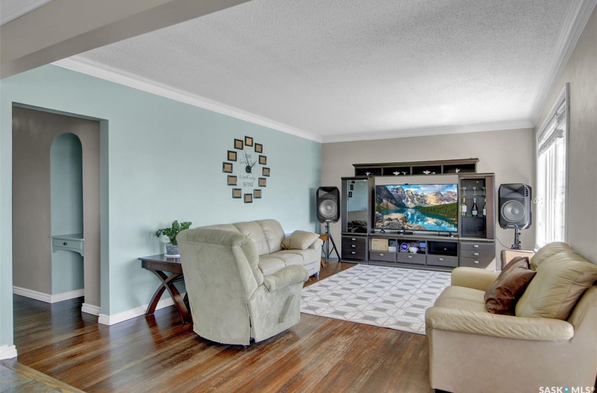 Living room featuring ornamental molding, wood-type flooring, and a textured ceiling