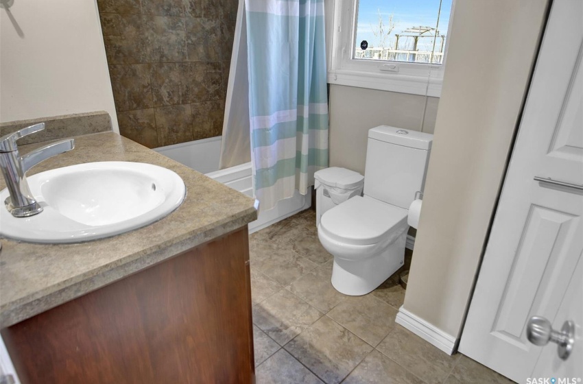 Full bathroom featuring shower / bathtub combination with curtain, toilet, tile floors, and vanity