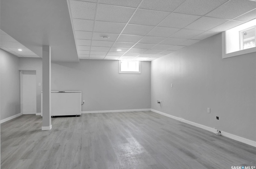 Basement with a drop ceiling and light wood-type flooring