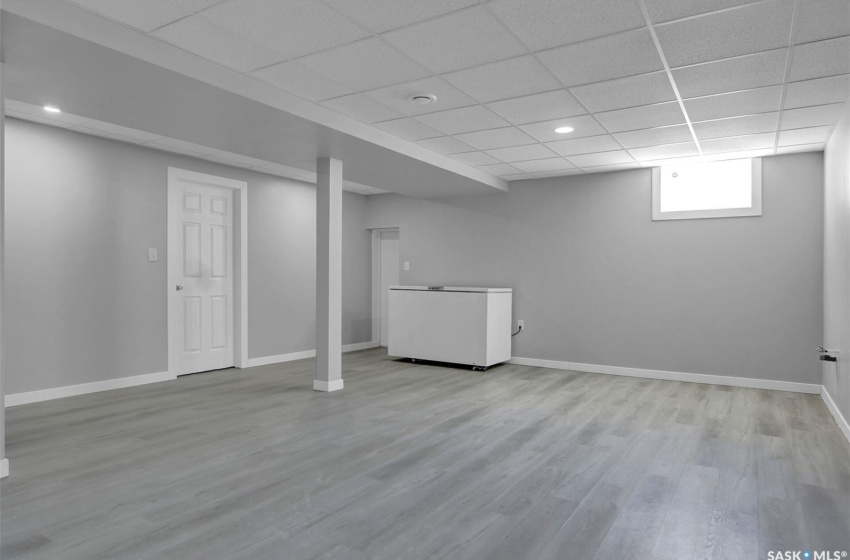 Basement with a drop ceiling and light wood-type flooring