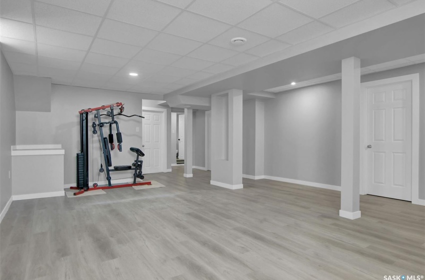 Exercise area with a drop ceiling and light hardwood / wood-style flooring