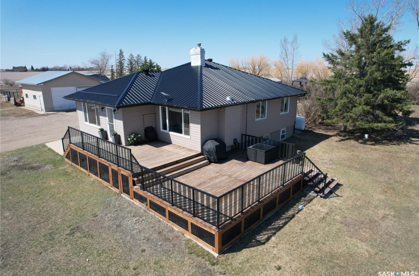 Back of house featuring a deck, a yard, an outdoor structure, and a garage