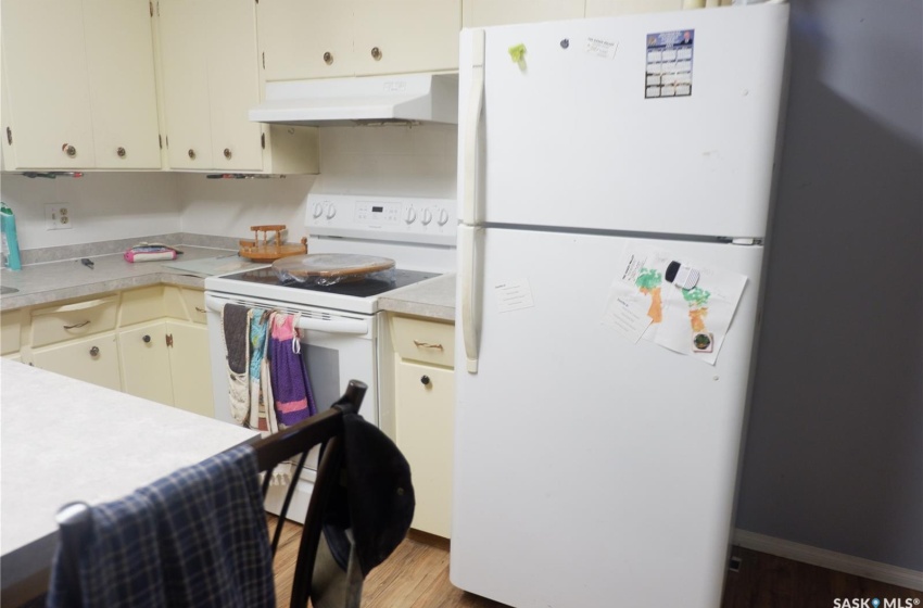 Kitchen with premium range hood, hardwood / wood-style flooring, white appliances, and cream cabinetry