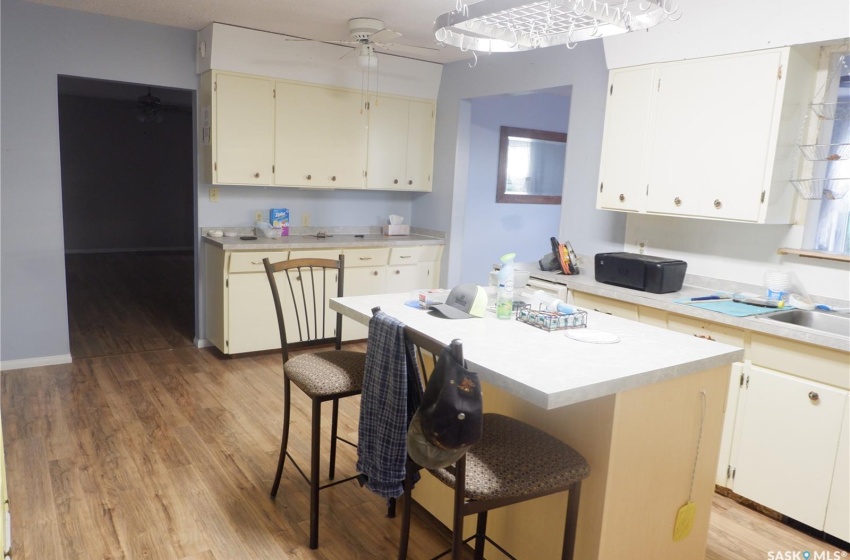 Kitchen featuring a kitchen breakfast bar, ceiling fan, light wood-type flooring, a kitchen island, and sink