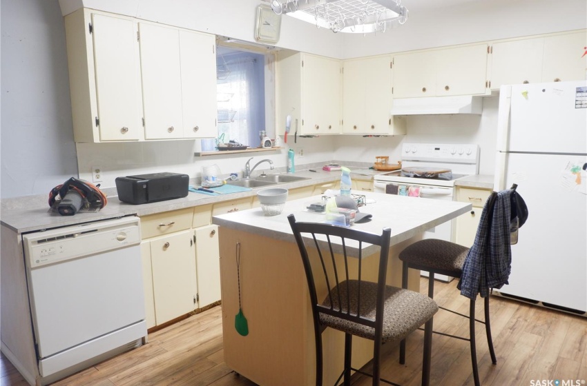 Kitchen with sink, white appliances, premium range hood, and light hardwood / wood-style flooring