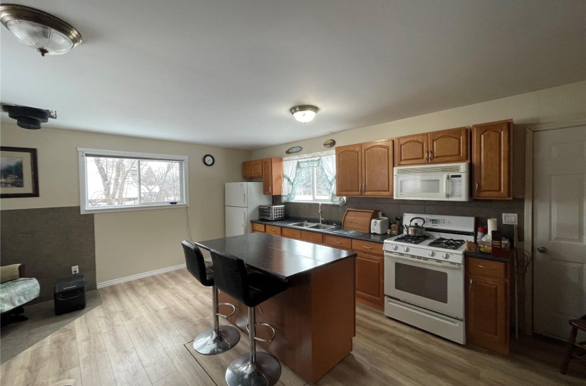 Kitchen with a kitchen bar, a kitchen island, white appliances, light hardwood / wood-style floors, and sink