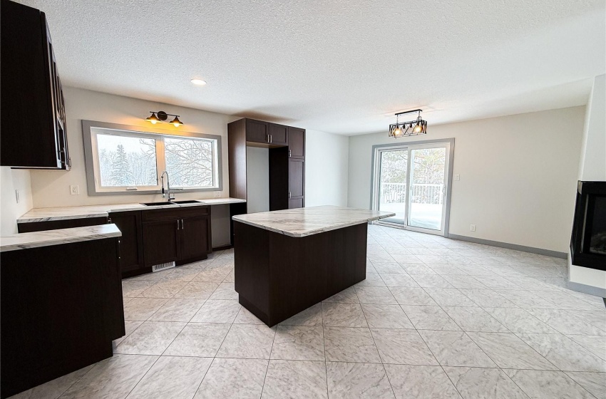 Kitchen with a center island, sink, an inviting chandelier, a textured ceiling, and light tile patterned floors