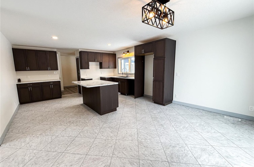 Kitchen featuring dark brown cabinetry, sink, a notable chandelier, a kitchen island, and hanging light fixtures