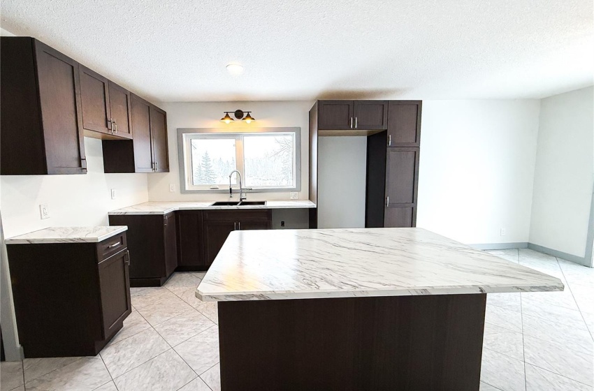 Kitchen featuring dark brown cabinets, sink, a center island, and a textured ceiling