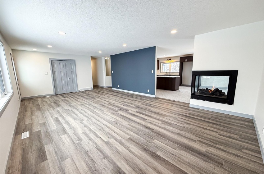 Unfurnished living room featuring a multi sided fireplace, a textured ceiling, and light hardwood / wood-style flooring