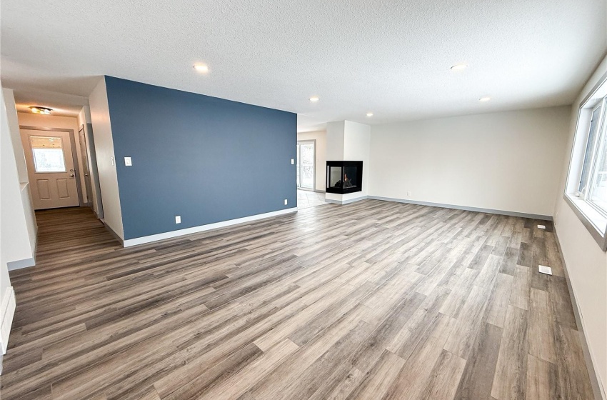 Unfurnished living room with a multi sided fireplace, a textured ceiling, and light hardwood / wood-style flooring