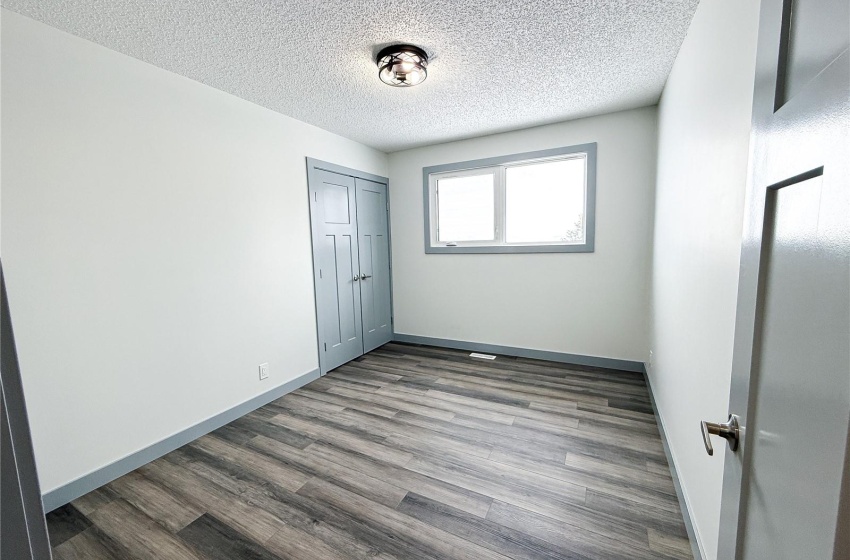 Unfurnished bedroom with wood-type flooring, a textured ceiling, and a closet