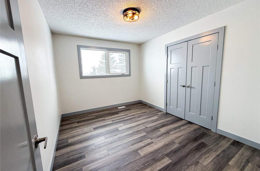 Unfurnished bedroom featuring a textured ceiling, dark hardwood / wood-style flooring, and a closet