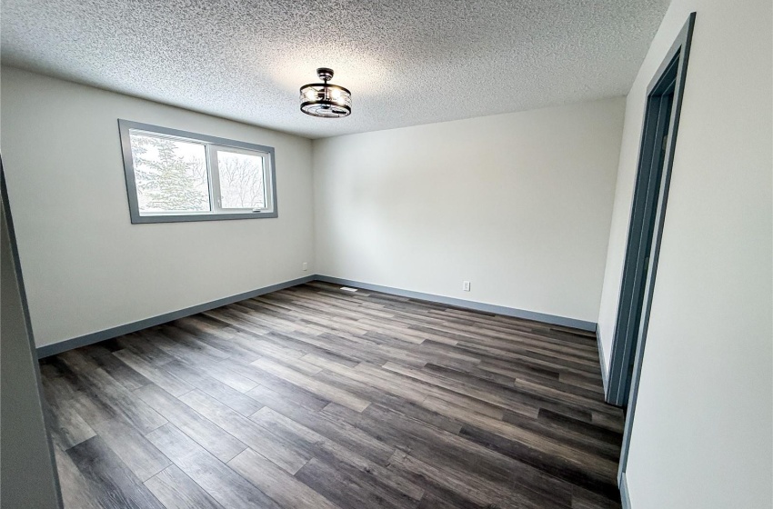 Empty room featuring a textured ceiling and dark hardwood / wood-style floors