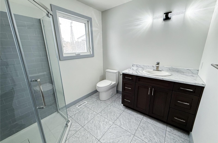 Bathroom with a shower with door, vanity, and toilet