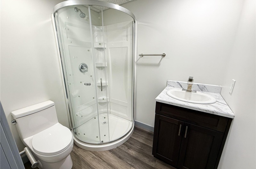 Bathroom featuring vanity, a drop ceiling, hardwood / wood-style flooring, toilet, and a shower with shower door