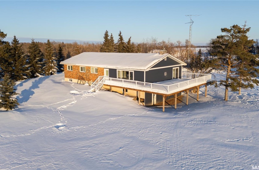 Snow covered back of property with a wooden deck