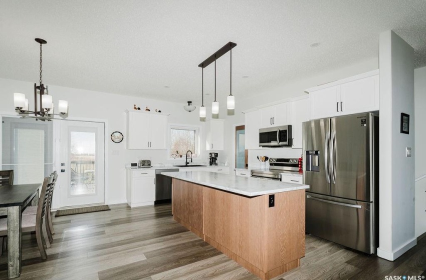 Kitchen with white cabinets, stainless steel appliances, hanging light fixtures, and a kitchen island