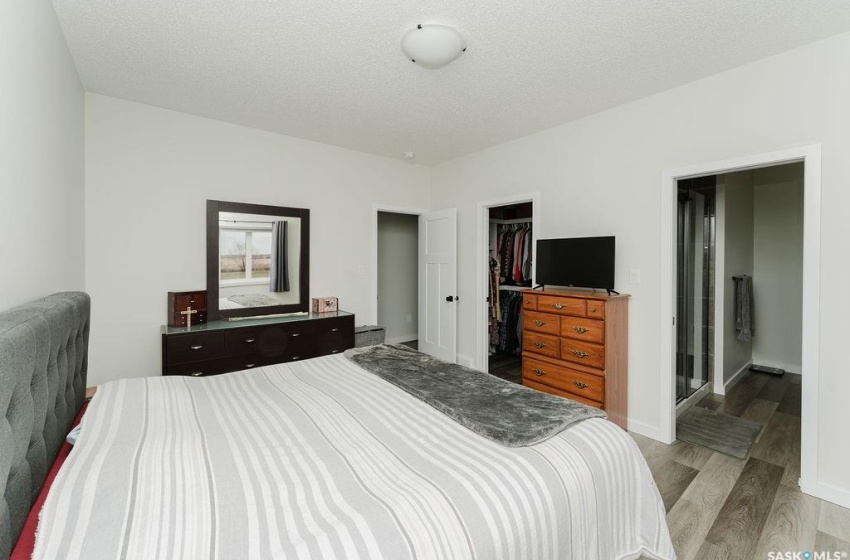 Bedroom with a spacious closet, light hardwood / wood-style flooring, a textured ceiling, and a closet