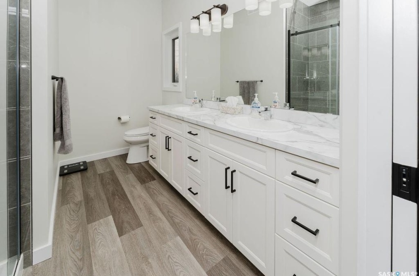 Bathroom with toilet, walk in shower, vanity, and hardwood / wood-style flooring