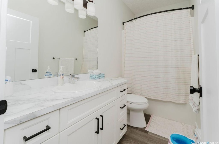 Full bathroom with vanity, hardwood / wood-style flooring, toilet, and shower / bathtub combination with curtain