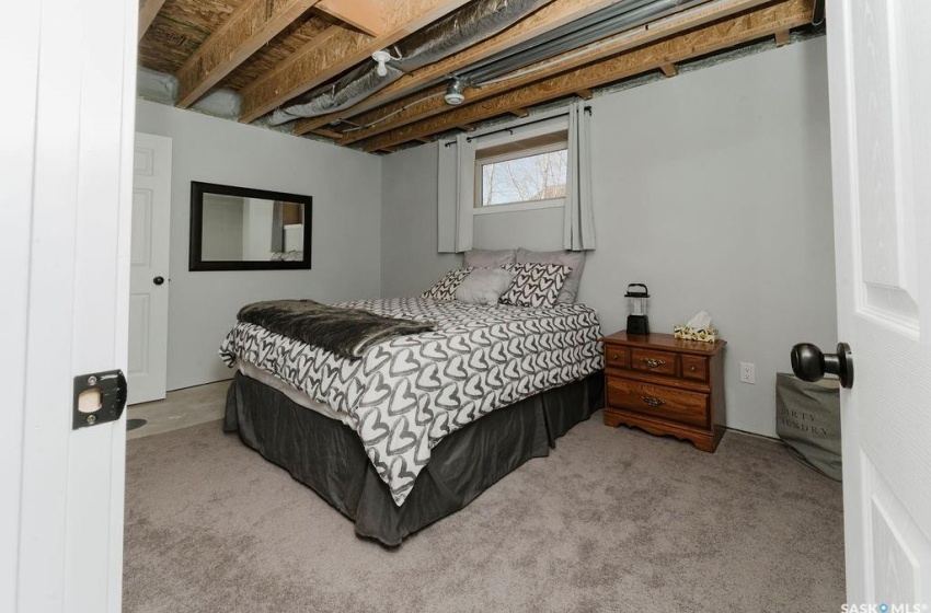 Bedroom with beam ceiling and light colored carpet