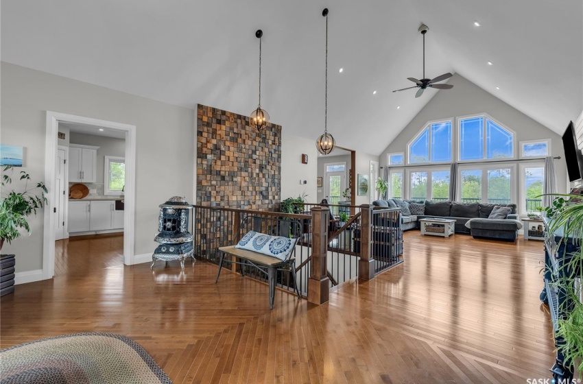 Living room with high vaulted ceiling, ceiling fan, and hardwood floors