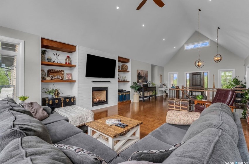 Living room featuring high vaulted ceiling, a fireplace, hardwood flooring, and ceiling fan