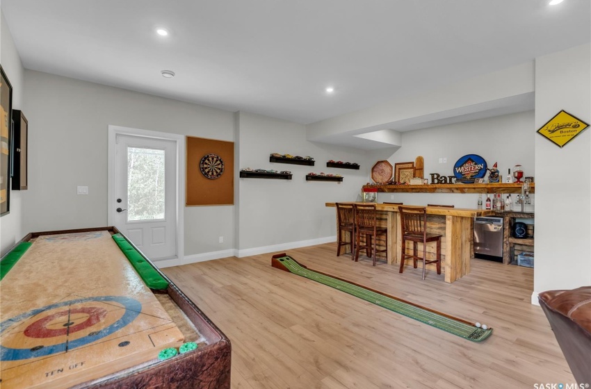 Game room with laminate plank flooring and bar area