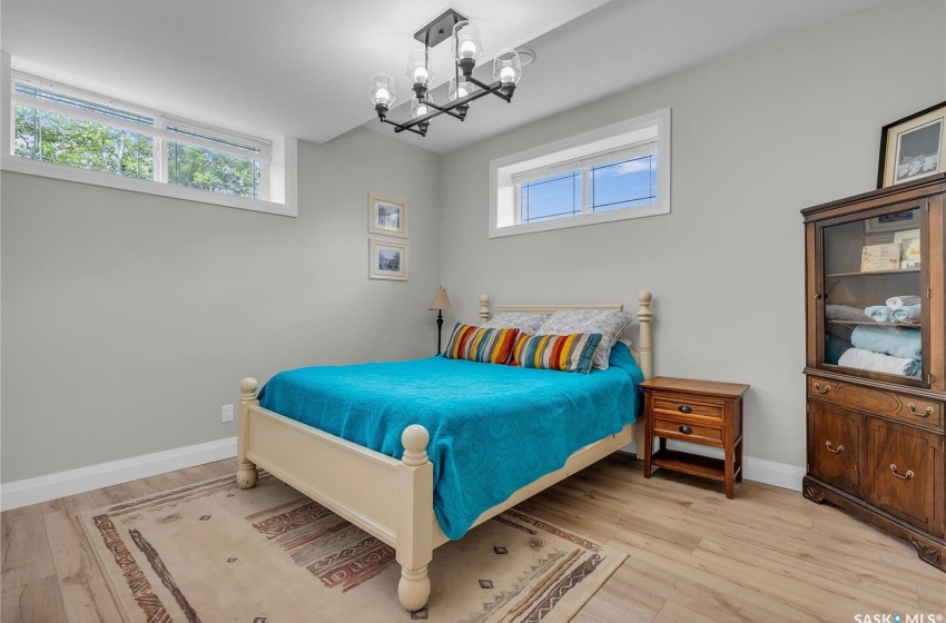 Bedroom featuring a chandelier, multiple windows, and laminate flooring