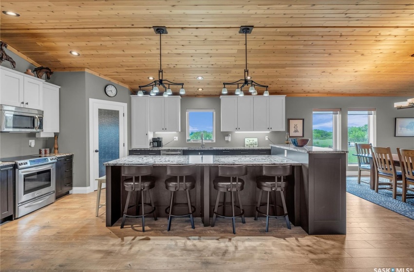 Kitchen with white cabinetry, hanging light fixtures, granite countertops, and appliances with stainless steel finishes