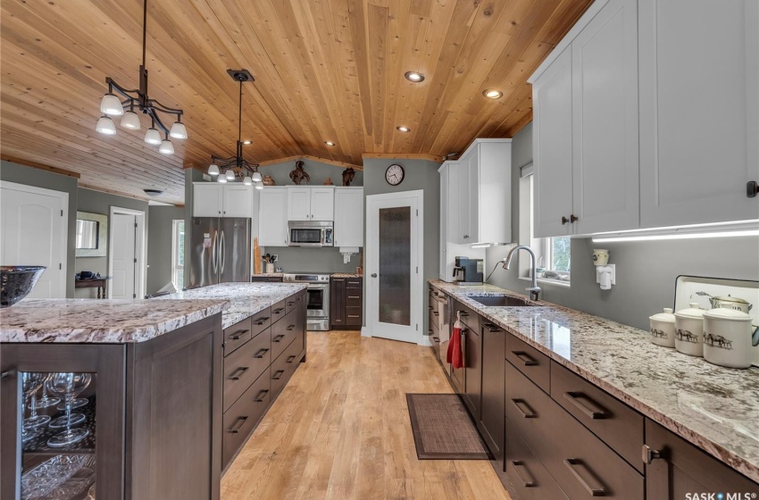 Kitchen with appliances with stainless steel finishes, white cabinets, decorative light fixtures, and sink