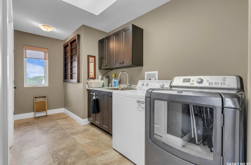 Laundry room with washing machine and dryer, sink, cabinets, and storage