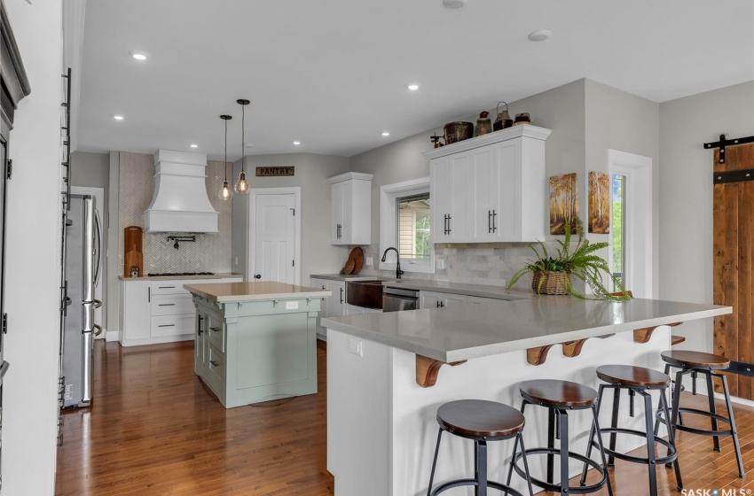 Kitchen featuring hardwood floors, tasteful backsplash, a barn door, custom range hood, and a center island