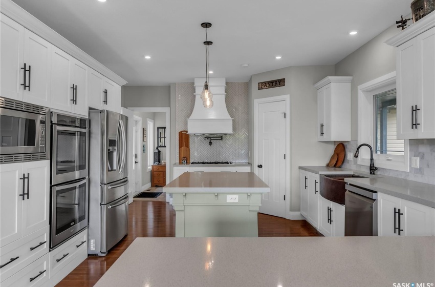 Kitchen featuring tasteful backsplash, stainless steel appliances, hardwood flooring, premium range hood, and a kitchen island